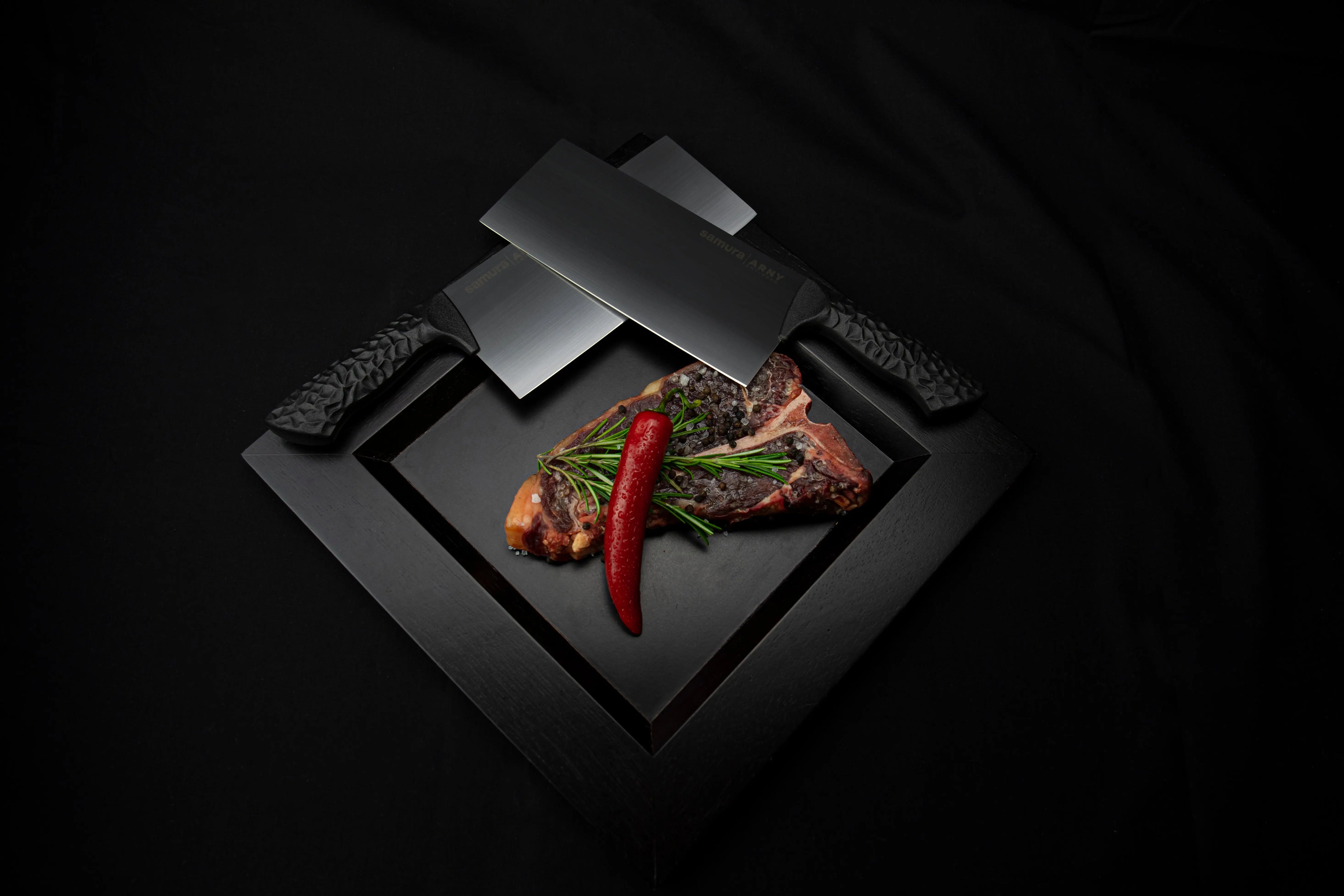 Precision Knives Samura Arny knives overlapping on a plate with a steak and a chilli pepper