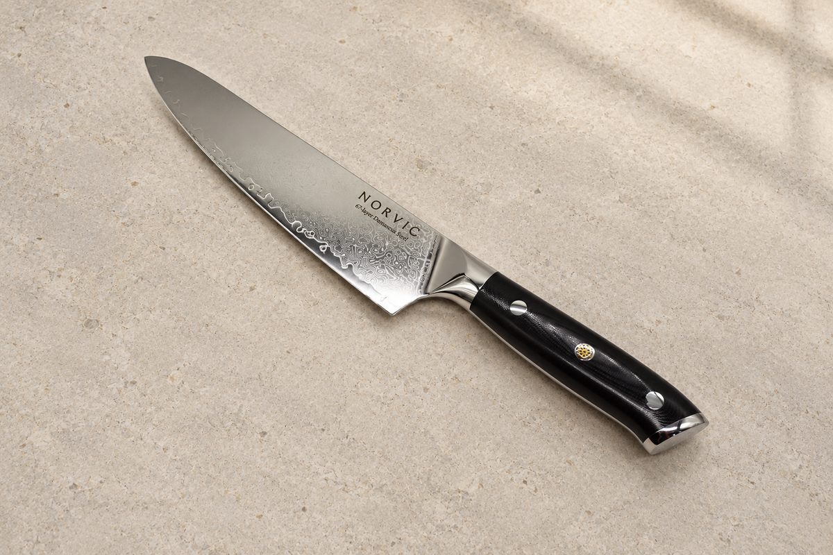 Norvic Worstead 8-inch chef knife, diagonal view on limestone with Damascus blade and black G10 handle