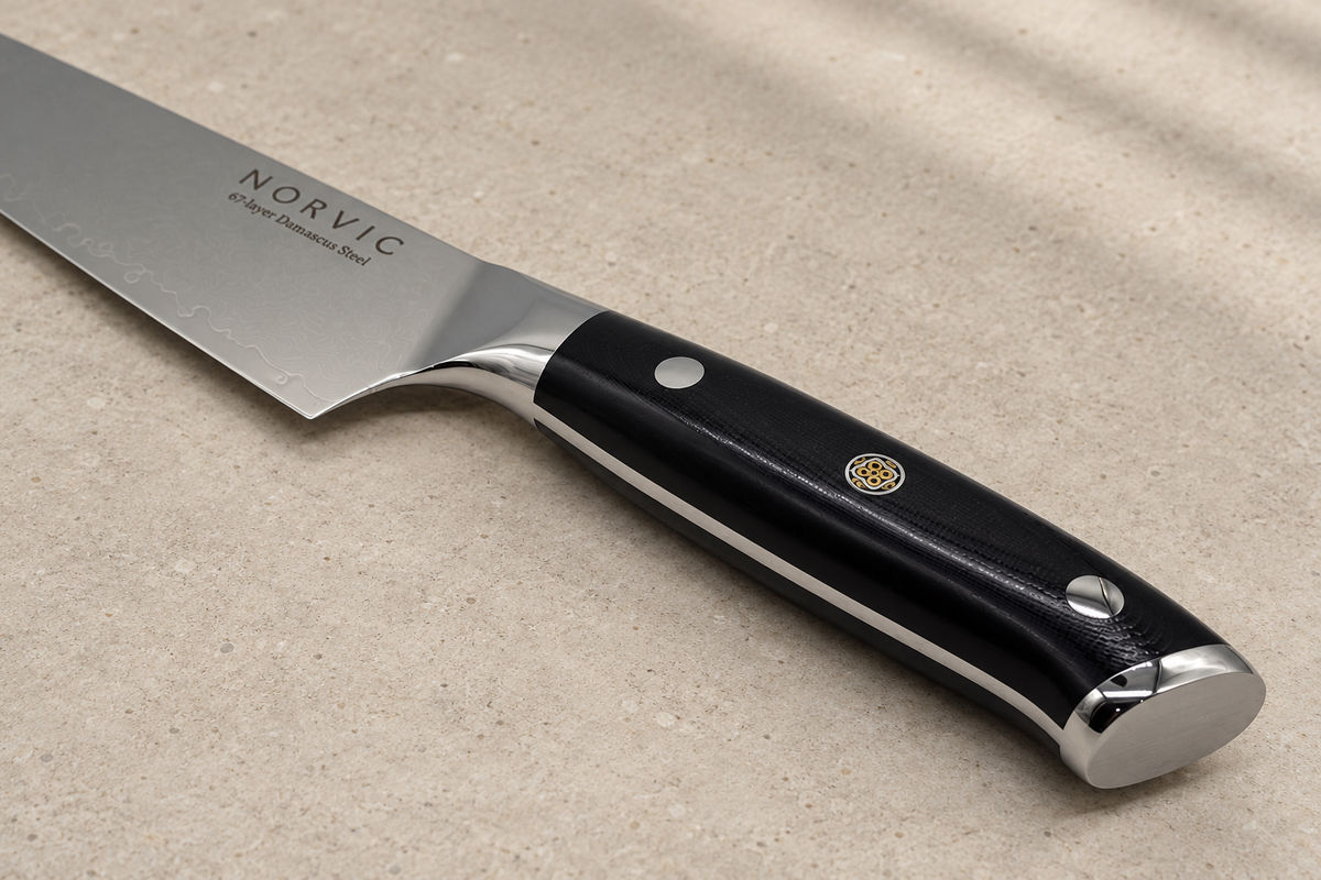 Closer view of the Norvic Worstead 8-inch chef knife, showing the black G10 handle, mosaic pin, bolster and Norvic engraving