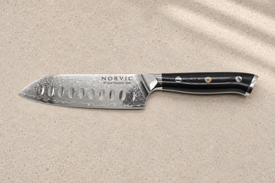 Side profile of the Norvic Worstead 5-inch santoku knife, showing its dimpled Damascus blade and black G10 handle