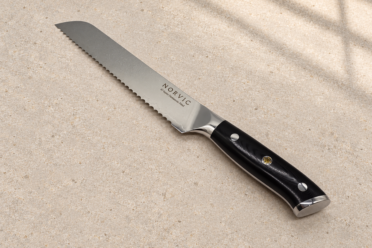 Norvic Worstead 8-inch bread knife, diagonal view on limestone with Damascus blade and black G10 handle