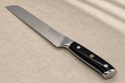 Closer view of the Norvic Worstead 8-inch bread knife, showing the black G10 handle, mosaic pin, bolster and Norvic engraving